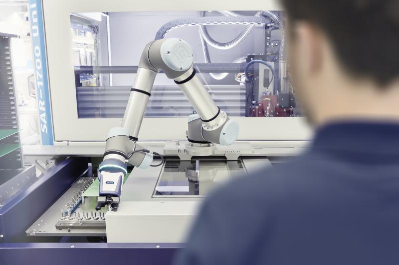 Teamwork in der Elektronikindustrie: Bei diesem Nutzentrenner unterstützt ein Roboterarm mit einem SCHUNK Co-act EGP-C Greifer den Bediener bei der Beladung. Bild: SCHUNK